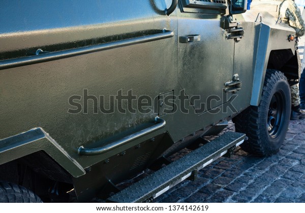 Wheels\
and part of the armored personnel carrier. Camouflage green color\
of military vehicles. Side view. Khaki\
background.