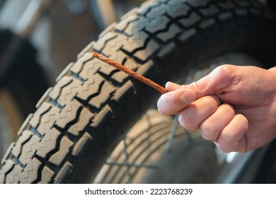 Wheels repair kit in the worker hand on the deflated motorcycle wheel close up. - Shutterstock ID 2223768239