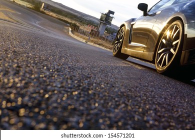 The wheels of a sport car at dusk, with the asphalt at foreground, in a racetrack. Car in a racetrack. - Shutterstock ID 154571201