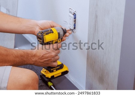 When constructing a house, electrician uses screwdriver to install an outlet on wall