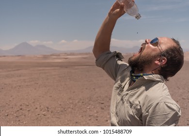 When the desert ties up your throat. The last drop of water in the desert has a bitterweet taste. Male with sunglasses drinking the last waterdrop of the bottle in the driest desert on earth: Atacama