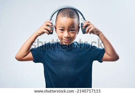 When I grow up I want to be a DJ. Studio shot of a cute little boy using headphones against a grey background.