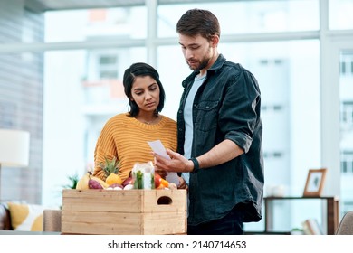 When Keeping Healthy Comes At A Cost. Shot Of A Young Couple Going Through Their Receipts At Home After Buying Groceries.