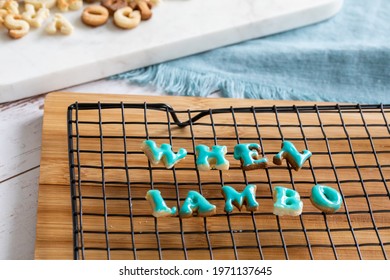 When lambo written in cookies drying on a metal grill on a wooden board with blue icing