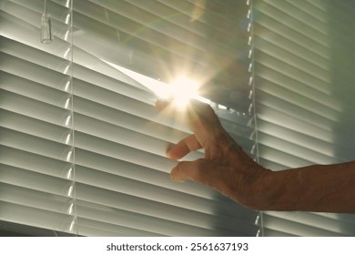 When a man's hand opens the window blinds, a bright blinding ray of sunlight streams in, filling the space with warmth and light, as if welcoming all the inhabitants of the house.