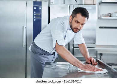 When Preparing Foods Keep It Clean, A Dirty Area Should Not Be Seen. Young Male Professional Cook Cleaning In Commercial Kitchen
