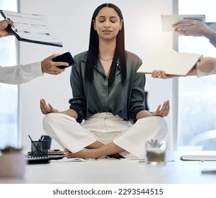 When you calm the inside, the outside will follow. Shot of a young businesswoman meditating on a desk in a demanding work environment. - Powered by Shutterstock