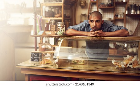 Where are all the customers. Shot of a young man standing behind the counter of his store and looking downhearted. - Powered by Shutterstock