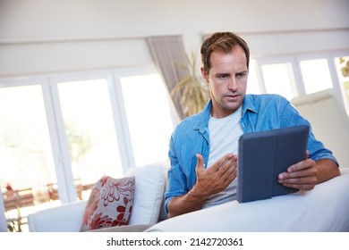 Where Did The Connection On This Thing Go Now. Shot Of A Man Looking Frustrated While Using A Digital Tablet At Home.