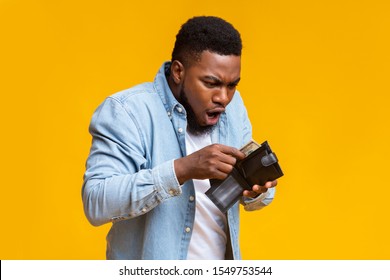 Where's My Money. Shocked African American Guy Holding Wallet With Dollar Cash That Will Be Not Enough To Cover Spendings, Yellow Studio Background.