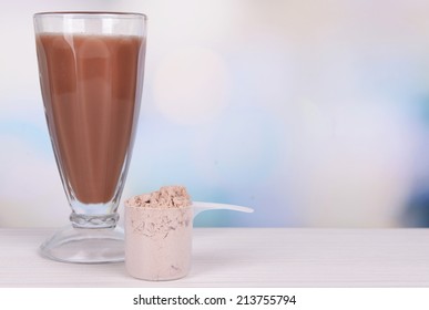 Whey Protein Powder And Chocolate Protein Shake On Table On Bright Background