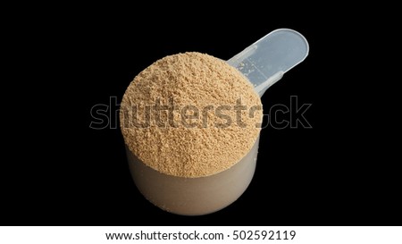 Whey protein powder scoop on a black background.