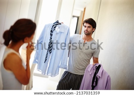 Which one do you think I should wear. Handsome man asking his wife what he should wear.