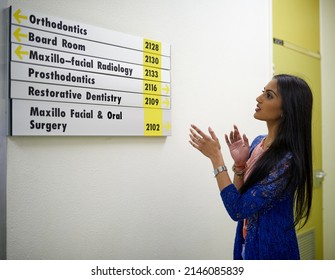 Which Way Should I Go. Shot Of An Attractive Young Woman Reading A Directory On The Wall Of A Medical Center.