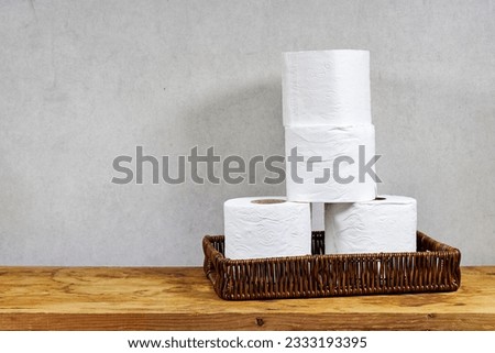 whicker basket with rolls of toilet paper on wooden board table with copy space 