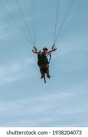 While enjoying the view, a man with a partner falls off the sky while parachuting