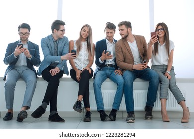 while waiting for the interview, a group of young people use gadgets