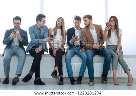 while waiting for the interview, a group of young people use gadgets