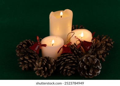 A whimsical holiday centerpiece showcasing lit candles, pinecones, and red bells, enhancing the festive spirit on a green background - Powered by Shutterstock