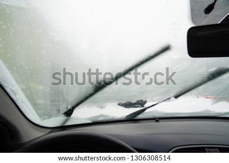 Whipers are pushing snow away form the steamy windshield. Cold winter morning.