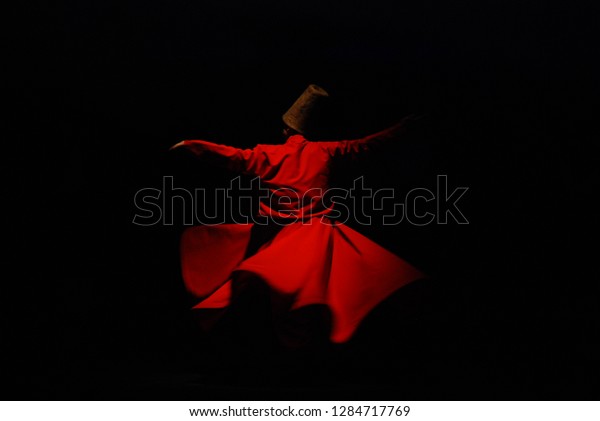 Whirling\
Dervish with red costume on black\
background