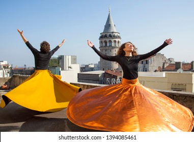 Whirling Dervishes or Semazen in Istanbul, Turkey. Galata Tower and city in background. Male and female dervish together 