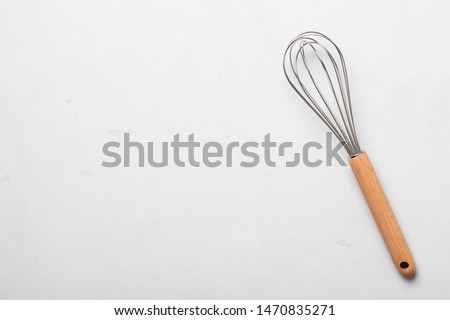 Whisk cooking egg beater mixer whisker new clean with wooden handle on stucco table top view