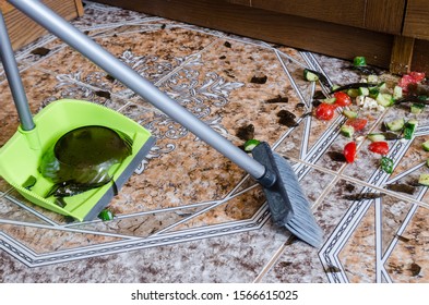 Whisk And Scoop Cleaning Broken Glass Plate With Food On Floor. Top View