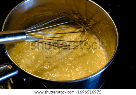 Whisk stirring flour and butter in pot making roux for sauce