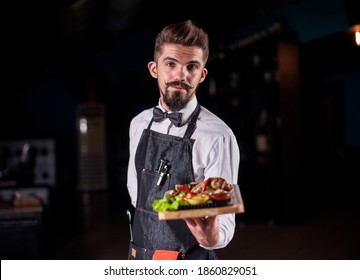 Whiskered Steward Holds Plate With Prepared Dish At A Festive Event.