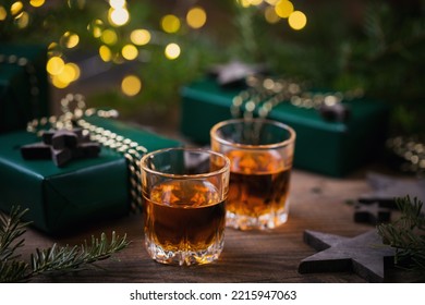 Whiskey, brandy or liquor shot and Christmas decorations on wooden background. Winter holidays concept.