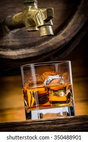 Whiskey Or Brandy Is Poured Into A Glass From Oak Barrel