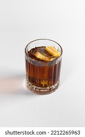 A Whiskey And Cola Cocktail Decorated With A Large Ice Cube And Caramel. On A White Isolated Background.