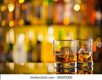 Whiskey Drinks On Bar Counter With Blur Bottles On Background