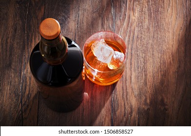 Whiskey Glass With Bottle And Ice On Wooden Bar Table. Overhead View.