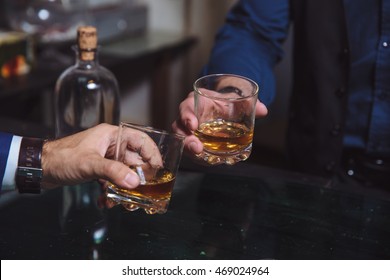 Whiskey glass in a hand of two mans - Powered by Shutterstock