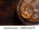 Whiskey glass with ice on a rustic barrel, a classic sip. With copy space