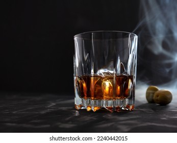 Whiskey glass on a bar counter with smoke and olives. low key photo - Powered by Shutterstock