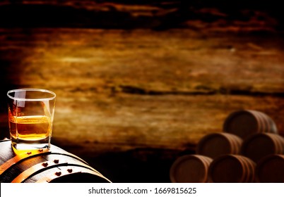 Whiskey Glass Stands On Whiskey Barrel In The Dark Cellar