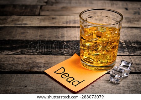 Whiskey in light pool and dead note on brown table