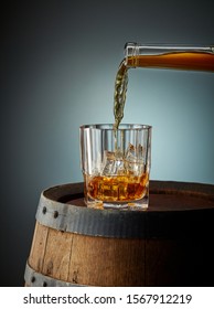 Whiskey Pouring Into Glass On Old Wooden Barrel