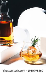 Whiskey, Scotch Or Bourbon Glass With Rosemary, Shard Ice On Black White Background With Geometric Cubes And Circles. Contemporary Still Life 