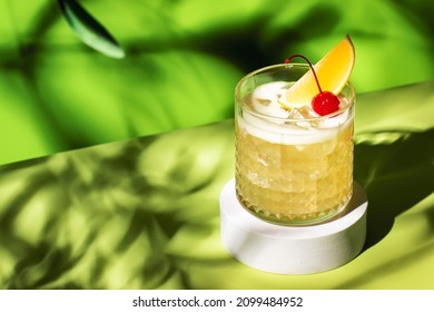 Whiskey sour trendy alcoholic cocktail with bourbon, lemon juice, egg white and ice, rocks glass on bright green background with hard light. Copy space