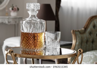 Whisky glass decanter hall-full with whisky liquor and an empty glass of whiskey with on glass table in cozy hotel inerior