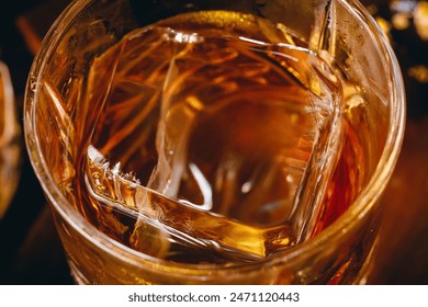 Whisky on the rocks. Glass of aged bourbon, whiskey, cognac, scotch filled with ice cube, close-up macro photo. Alcohol, hard drink concept