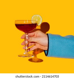 Whisky, Rum. Bitter And Sweet. Female Hand Holding Glass With Manhattan Cocktail Isolated On Bright Yellow Neon Background. Yellow, Red And Blue. Copy Space For Ad. Pop Art, Retro, Vintage Style