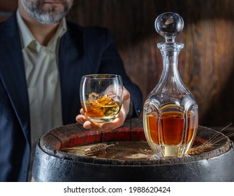 Whisky Tasting. Man Sits In Front Of A Barrel With A Decanter And A Glass Of Whiskey.