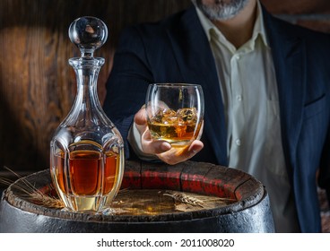 Whisky Tasting. Man Sits In Front Of A Barrel With A Decanter And A Glass Of Whiskey.