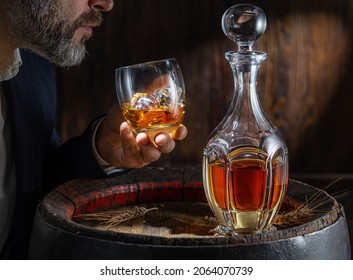 Whisky Tasting. Man Sits In Front Of A Barrel With A Decanter And A Glass Of Whiskey.