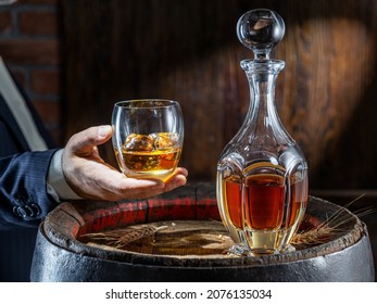 Whisky Tasting. Man Sits In Front Of A Barrel With A Decanter And A Glass Of Whiskey.